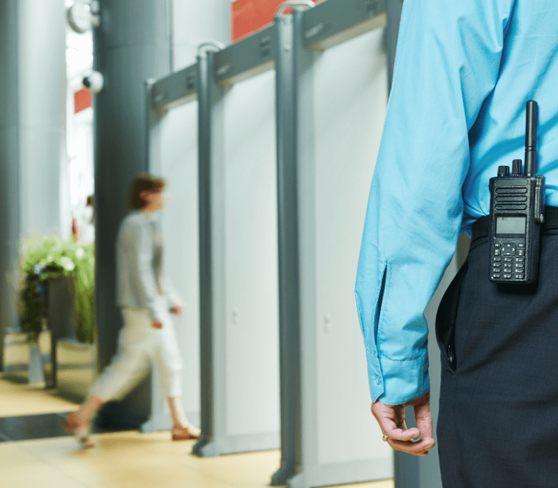 a lady exiting a building and security guard with a walkie talkie