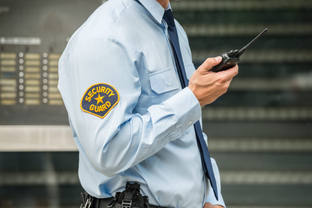 A security guard holding a walkie talkie radio.